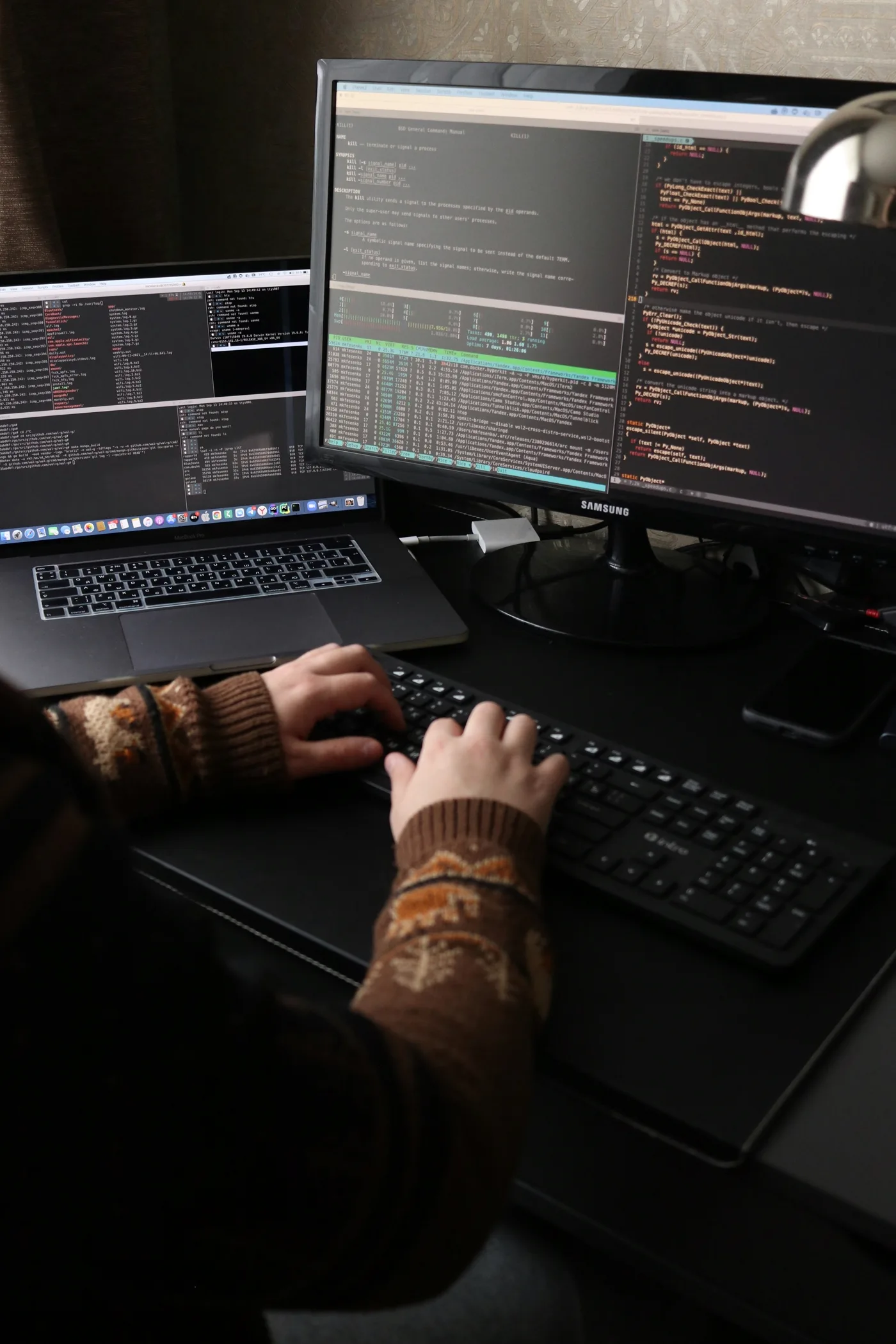 Person working at a desk with laptop and monitor building backend infrastructure