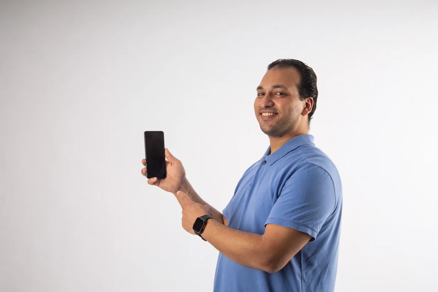 Confident man smiling while holding his phone showing a launched mobile app