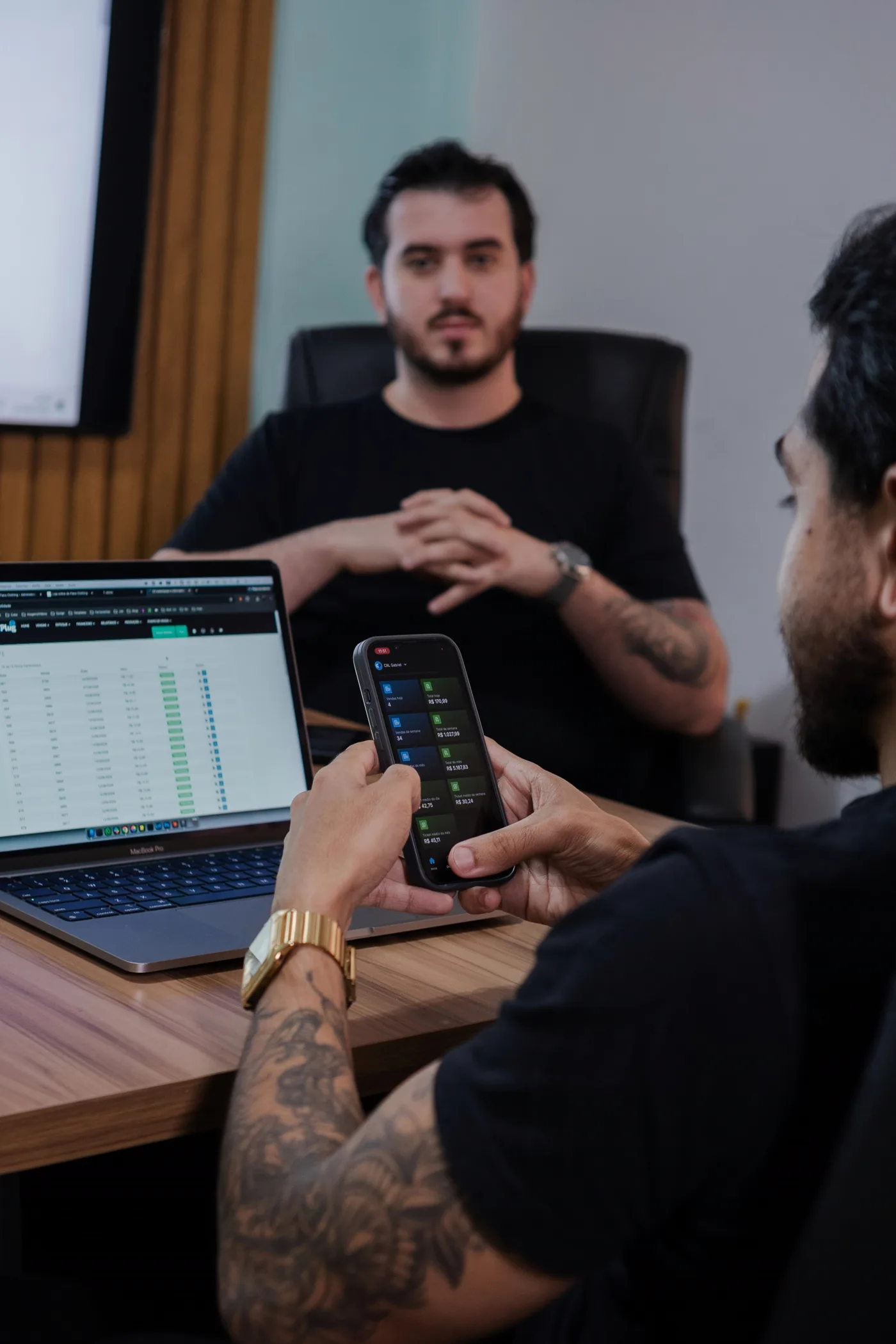 Team member reviewing a mobile app on his phone while a colleague looks on in the office