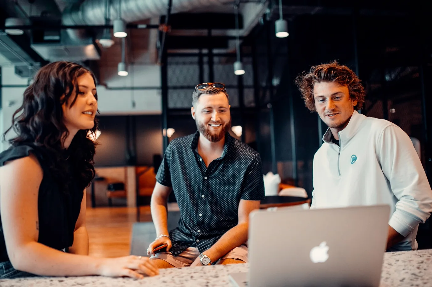 Three colleagues reviewing a laptop together, discussing a connected systems integration