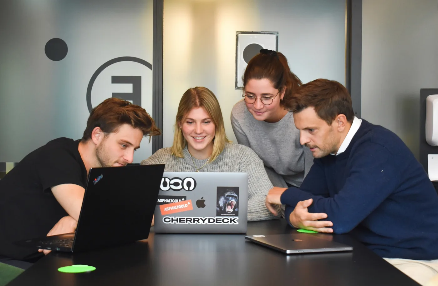 A software engineering team smiling together while reviewing a build on a laptop