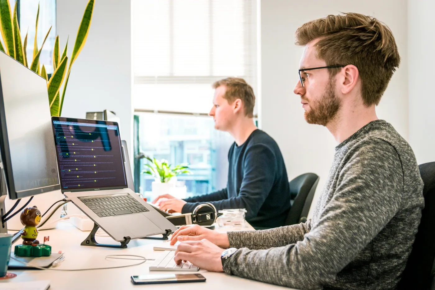 Two focused software engineers working side by side in a bright, modern office