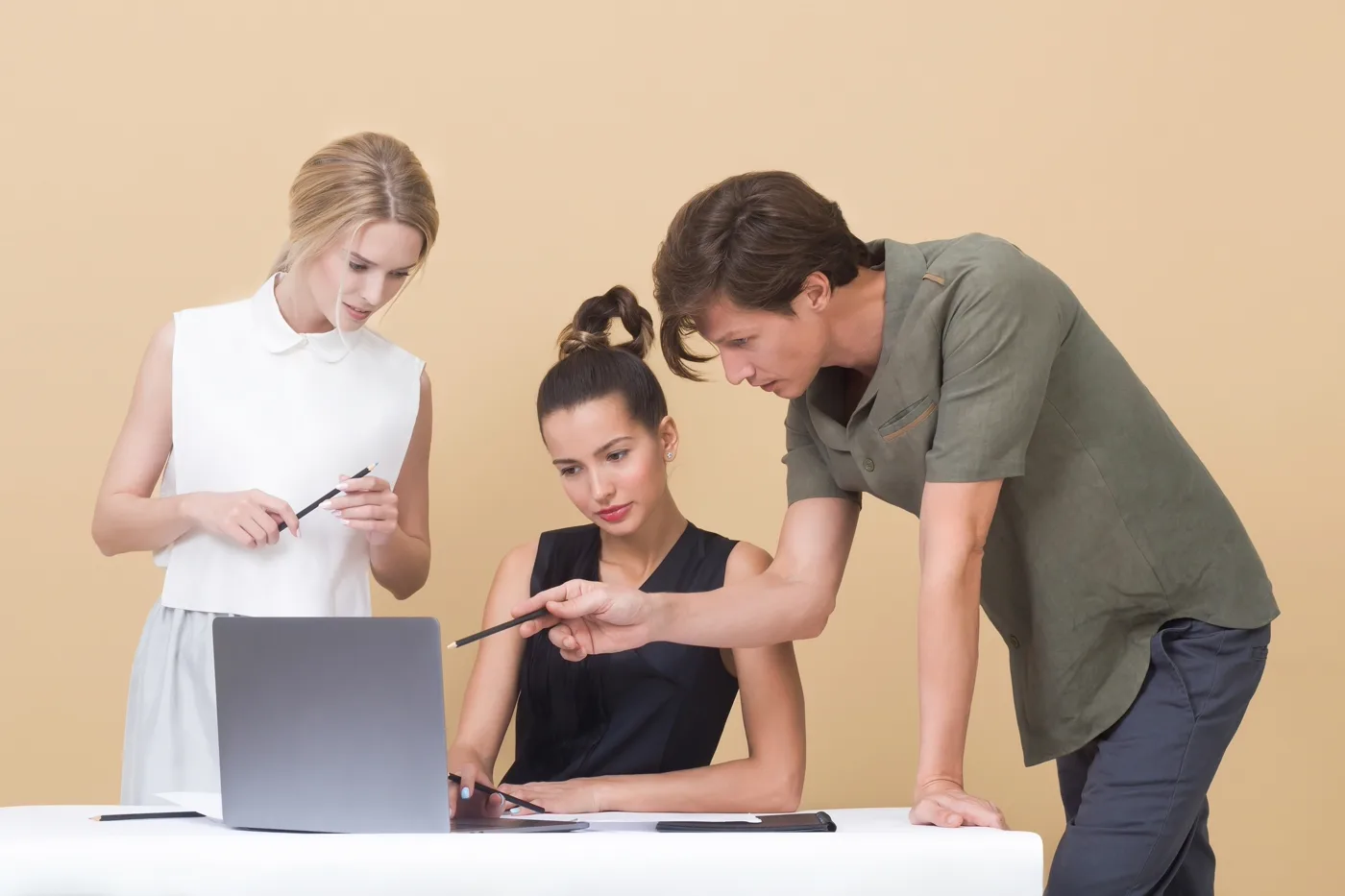 Designer pointing at a laptop screen while walking a colleague through an interface design