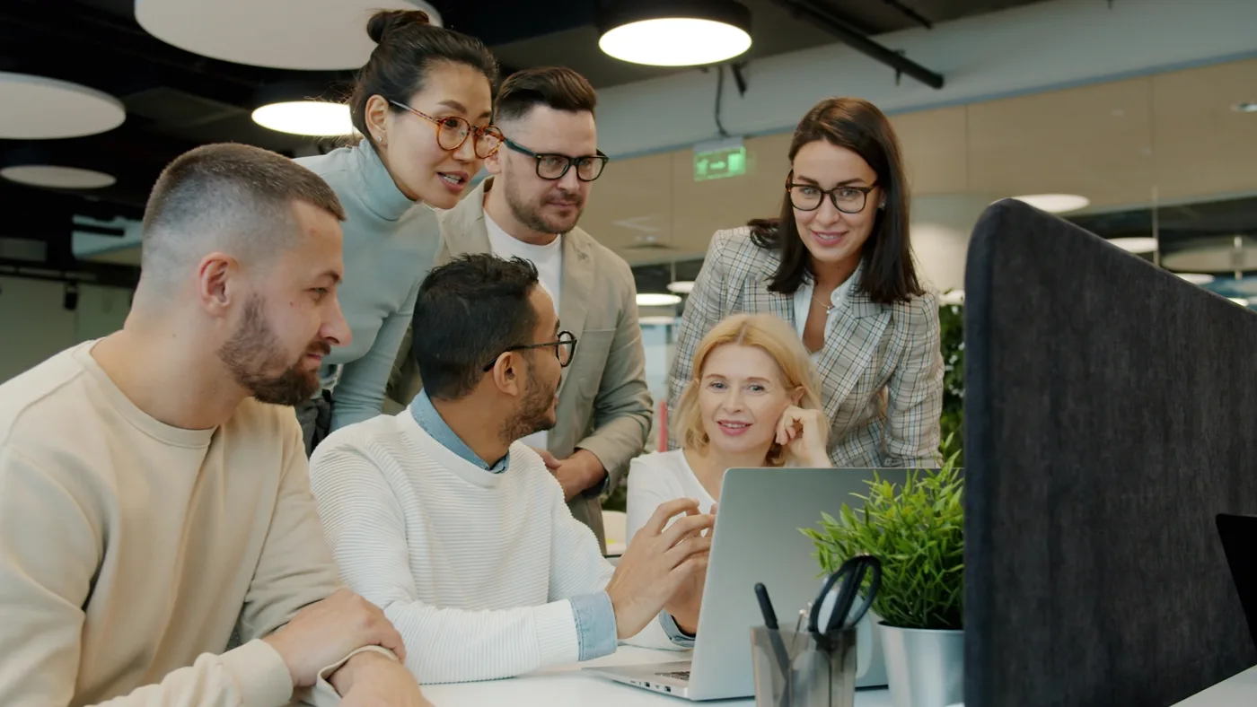 Diverse design team collaborating around a laptop, mapping out information architecture
