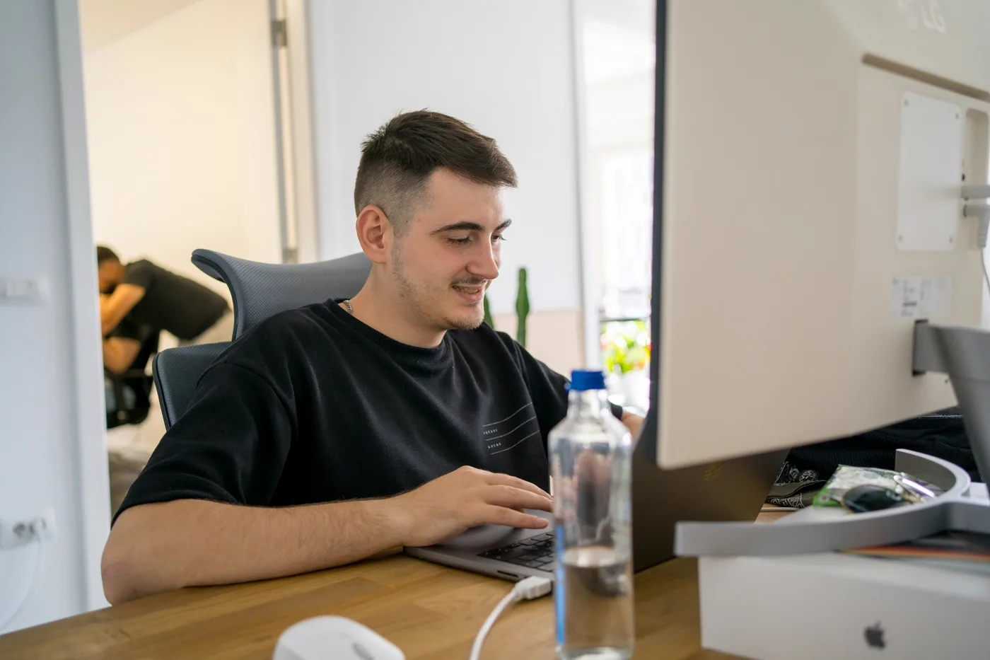 Focused developer coding at a desk in a bright modern office